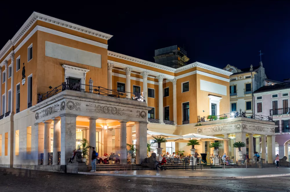 Padua, Italy - October 1, 2023: Caffe' Pedrocchi in the evening, located in the center of Padua, is a historic cafe of international fame. People sitting at the outdoor tables.