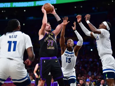 Mar 10, 2026; Los Angeles, California, USA; Los Angeles Lakers guard Luka Doncic (77) shoots against the defense of Minnesota Timberwolves center Naz Reid (11) guard Ayo Dosunmu (13) and forward Jaden McDaniels (3) during the first half at Crypto.com Arena. Mandatory Credit: Gary A. Vasquez-Imagn Images