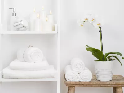 Shelf with clean towels, candles, flowerpot on bathroom wooden table