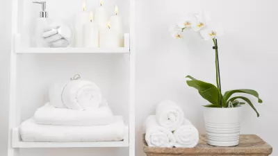 Shelf with clean towels, candles, flowerpot on bathroom wooden table