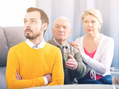 Aged grandfather teaches and instructs his young grandson in front of his mother