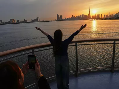 Women enjoy the sunset with the view of the city skyline and Burj Khalifa, at Dubai Creek Harbour in Dubai, United Arab Emirates, Wednesday, March 11, 2026. (AP Photo/Fatima Shbair)