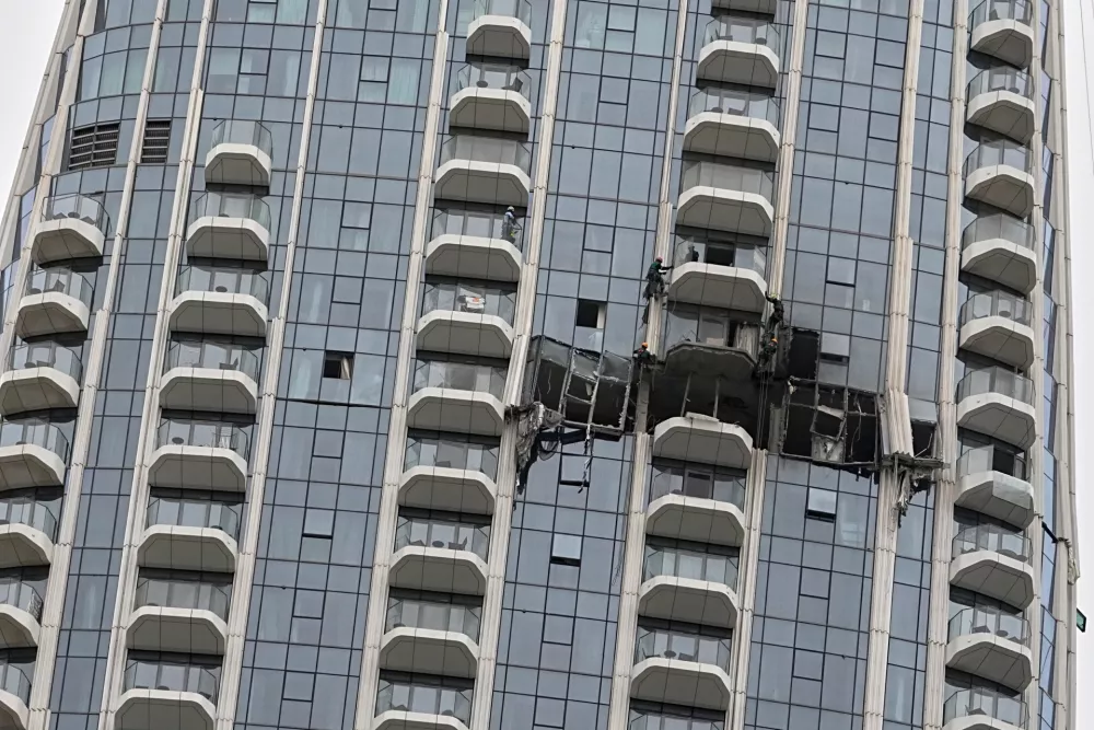 Workers inspect damage caused by a drone strike overnight at the Address Creek Harbour hotel in Dubai, United Arab Emirates, March 12, 2026. (AP Photo/Fatima Shbair)