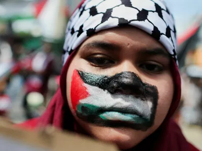A pro-Palestine supporter paints her face with the Palestinian flag during a rally to the U.S. Embassy to mark al-Quds (Jerusalem) Day, initiated by Ruhollah Khomeini, leader of Iran's 1979 Islamic Revolution, and observed on the last Friday of the Muslim fasting month of Ramadan to show solidarity with Palestinians and opposition to Zionism, in Kuala Lumpur, Malaysia, March 13, 2026. REUTERS/Hasnoor Hussain