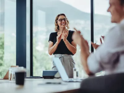 Businesswoman clapping hands after a successful conference meeting in office. Business people clapping after presentation in boardroom.