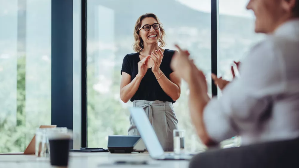 Businesswoman clapping hands after a successful conference meeting in office. Business people clapping after presentation in boardroom.