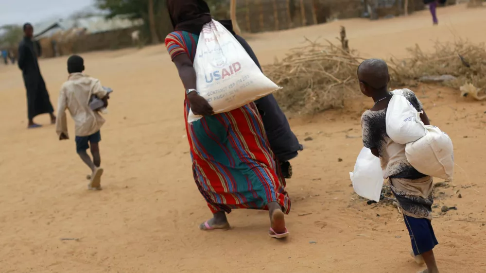A newly arrived Somali family carry their supply of aid outside Dadaab, Eastern Kenya, 100 kms (60 miles) from the Somali border, Friday Aug. 5, 2011. Somali government troops opened fire Friday in Mogadishu on hungry civilians, killing at least seven people, as both groups made a grab for food at a U.N. distribution site in the capital of this famine-stricken country, witnesses said. The drought and famine in the horn of Africa has killed more than 29,000 children under the age of 5 in the last 90 days in southern Somalia alone, according to U.S. estimates. The U.N. says 640,000 Somali children are acutely malnourished, suggesting the death toll of small children will rise. (AP Photo/Jerome Delay)