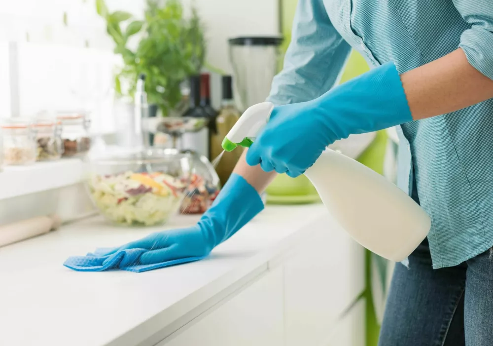 Woman cleaning and polishing the kitchen worktop with a spray detergent, housekeeping and hygiene concept / Foto: Demaerre
