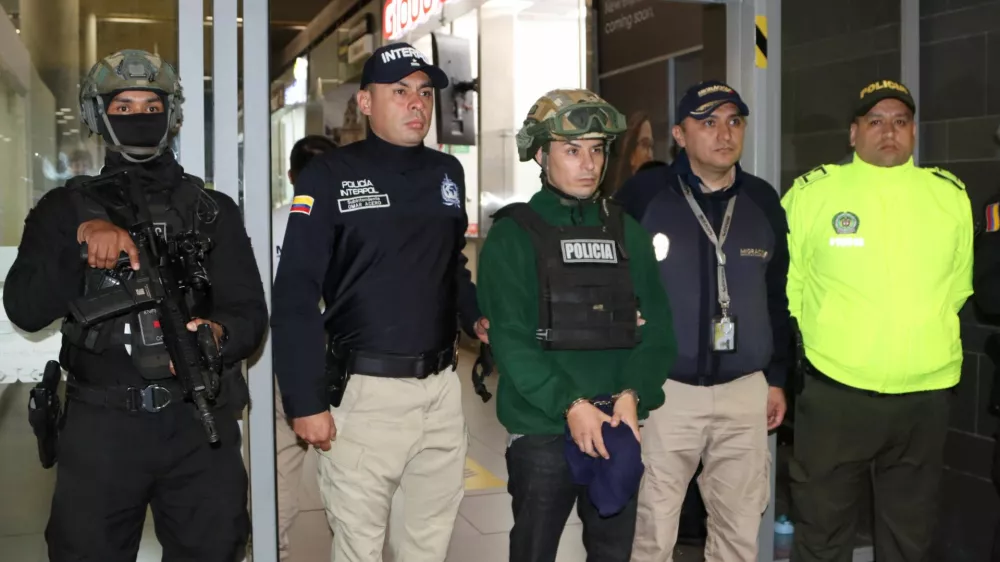 Colombian police officers escort a man identified as Angel Esteban Aguilar, a leader of Ecuador's Los Lobos crime group, after his arrest, who is wanted in connection with the 2023 assassination of Ecuadorean presidential candidate Fernando Villavicencio, at the international airport El Dorado in Bogota, Colombia, March 18, 2026. Colombian Migration/Handout via REUTERS THIS IMAGE HAS BEEN SUPPLIED BY A THIRD PARTY. MANDATORY CREDIT. NO RESALES. NO ARCHIVES.