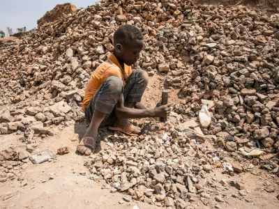 Children work in an aggregate mining site, Kolwezi. As a climate emergency approaches, industries across the world slowly begin to adapt and change. Demand soars for materials needed for renewable technologies, with cobalt and copper more essential than ever for use in electric vehicle batteries and other cutting-edge applications. Around two thirds of Earth's deposits of the ores that contain cobalt, as well as vast reserves of copper, are found in the dusty southern provinces of the Democratic Republic of Congo. With a renewed interest from the global community, billions of dollars flow in and out of Congo. Multinational companies vie for rights to mineral deposits and Congolese politicians create a fruitful niche for themselves in the sale of contracts and site access around the mining town of Kolwezi. Little of this wealth comes to those who live and work here, as communities find themselves exploited, poisoned and excluded from the riches of the green minerals of the electric future.,Image: 804607234, License: Rights-managed, Restrictions:, Model Release: no
