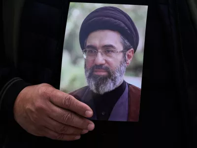 A man holds a poster of the Iranian Supreme Leader Ayatollah Mojtaba Khamenei during the funeral procession of Gen. Ali Mohammad Naeini, a spokesperson for Iran's paramilitary Revolutionary Guard and one of his comrades Amir Hossein Bidi in Tehran, Iran, Saturday, March 21, 2026. (AP Photo/Vahid Salemi)