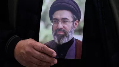 A man holds a poster of the Iranian Supreme Leader Ayatollah Mojtaba Khamenei during the funeral procession of Gen. Ali Mohammad Naeini, a spokesperson for Iran's paramilitary Revolutionary Guard and one of his comrades Amir Hossein Bidi in Tehran, Iran, Saturday, March 21, 2026. (AP Photo/Vahid Salemi)