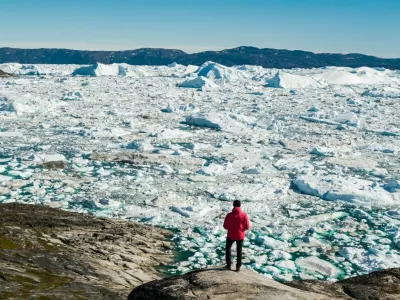 Travel in arctic landscape nature with icebergs - Greenland tourist man explorer - tourist person looking at amazing view of Greenland icefjord - aerial drone image. Man by ice and iceberg, Ilulissat. / Foto: Maridav
