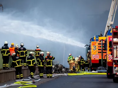 25 August 2025, Hamburg: Firefighters try to extinguish a fire in an industrial area in the port of Hamburg. A fire has broken out in a warehouse in the Port of Hamburg, causing a major motorway nearby to be closed. Photo: Daniel Bockwoldt/dpa