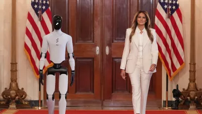 First lady Melania Trump arrives, accompanied by a robot, to attend the "Fostering the Future Together Global Coalition Summit," with other first spouses, at the White House, Wednesday, March 25, 2026, in Washington. (AP Photo/Jacquelyn Martin)