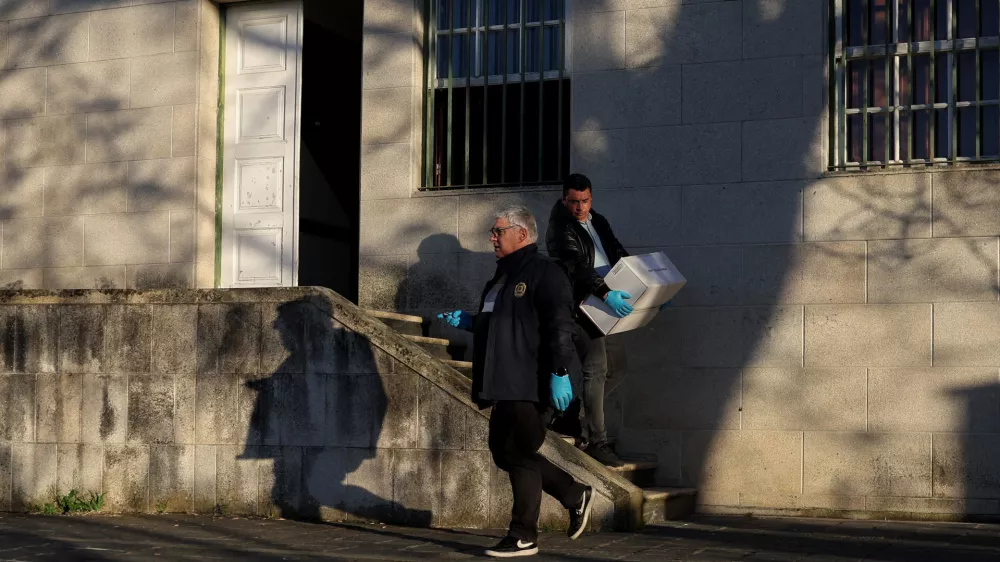 A police investigator carries a box related to the process of a French citizen who is answering before a judge, on the case of two women who were found buried in Braganca, in Vila Nova de Foz Coa courthouse, Portugal, March 26, 2026. REUTERS/Pedro Nunes