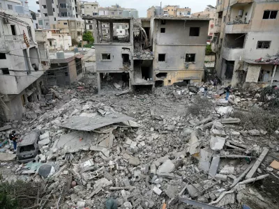 Journalists check the site of a destroyed building that was hit in an Israeli airstrike in the southern port city of Tyre, Lebanon, Thursday, March 26, 2026. (AP Photo/Hussein Malla)