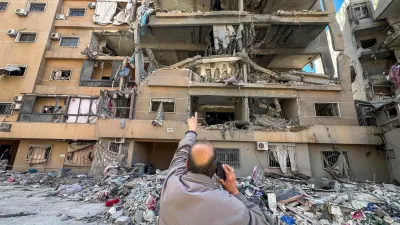 A man points at a building damaged by Israeli strikes, amid escalating hostilities between Israel and Hezbollah, as the U.S.-Israeli conflict with Iran continues, in Beirut's southern suburbs, Lebanon, March 28, 2026. Picture taken with a mobile phone. REUTERS/Stringer   TPX IMAGES OF THE DAY