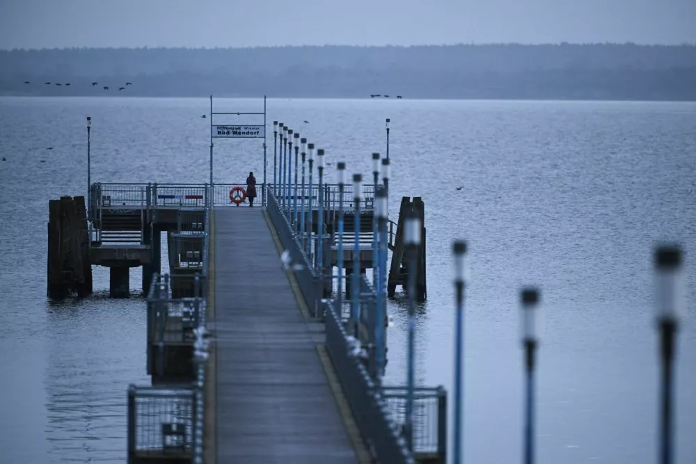 A woman stands on a bridge in the morning at Wismar Bay in the Baltic Sea, where a humpback whale (not pictured) is stuck in the shallow waters after having moved overnight, near Wismar, Germany March 29, 2026. REUTERS/Annegret Hilse / Foto: Annegret Hilse