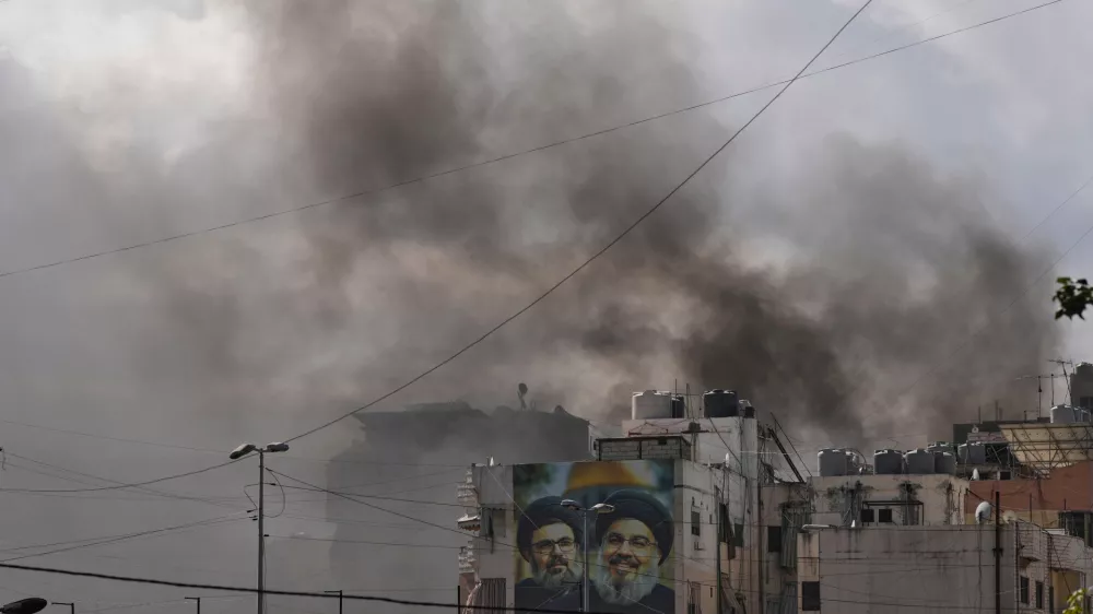 Portraits of Hezbollah's late leaders Hassan Nasrallah, right, and his cousin, Hashem Safieddine, are seen, as smoke rises following an Israeli airstrike in Dahiyeh, Beirut's southern suburbs, Lebanon, Monday, March 30, 2026. (AP Photo/Hassan Ammar)