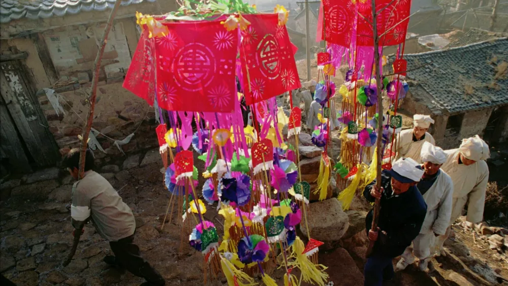 A funeral procession passes through Xin Village in China's Shanxi province, led by family members carrying paper decorations Sunday November 10, 1996. Though elaborate funerals are now rare in China's cities, in rural areas old traditions are still followed. Though China's government has made cremation compulsory, to save valuable land space, in rural areas the dead are often buried on the land in accordance with tradition. (AP Photo)