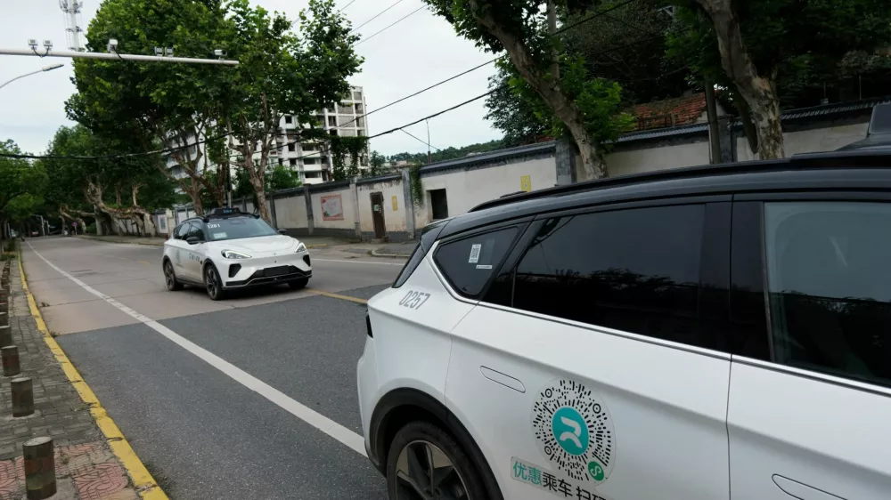 FILE PHOTO: A driverless car by Apollo Go, Baidu's robotaxi service, drives past another Apollo Go robotaxi parked on the side of a road, in Wuhan, Hubei province, China July 19, 2024. REUTERS/Ethan Wang/File Photo