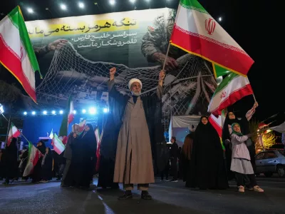 A Shiite cleric holds an Iranian flag during a pro-government gathering in a square in Tehran, Iran, Sunday, April 5, 2026. (AP Photo/Francisco Seco)