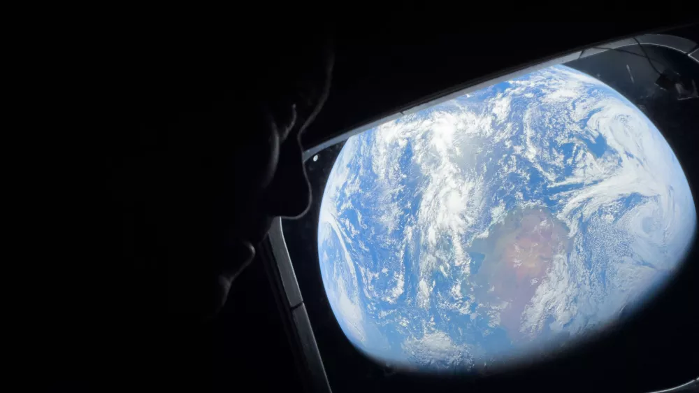  This image provided by NASA, astronaut and Artemis II Commander Reid Wiseman peers out of one of the Orion spacecraft's main cabin windows, looking back at Earth, as the crew travels towards the Moon on Thursday, April 2, 2026. (NASA via AP)