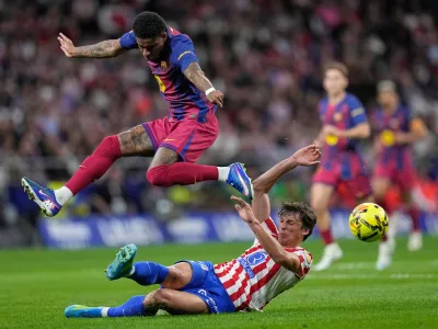 Atletico Madrid's Robin Le Normand, slides into tackle Barcelona's Marcus Rashford who leaps clear during a La Liga soccer match between Atletico Madrid and Barcelona in Madrid, Spain, Saturday, April 4, 2026. (AP Photo/Bernat Armangue)
