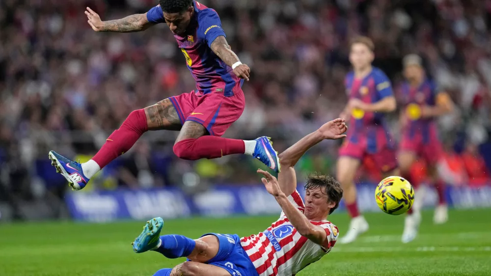 Atletico Madrid's Robin Le Normand, slides into tackle Barcelona's Marcus Rashford who leaps clear during a La Liga soccer match between Atletico Madrid and Barcelona in Madrid, Spain, Saturday, April 4, 2026. (AP Photo/Bernat Armangue)