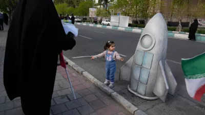 A girl stands next to replica of a space craft in a memorial for school children who were killed during a strike on a school in southern town of Minab on Feb. 28, in downtown Tehran, Iran, Tuesday, April 7, 2026. (AP Photo/Vahid Salemi)