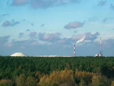 Industrial chemical plant in Gomel, Belarus. A large white mound of chemical waste rises behind a green forest, symbolizing pollution and the environmental impact of industry. / Foto: Viktoryia Malinava