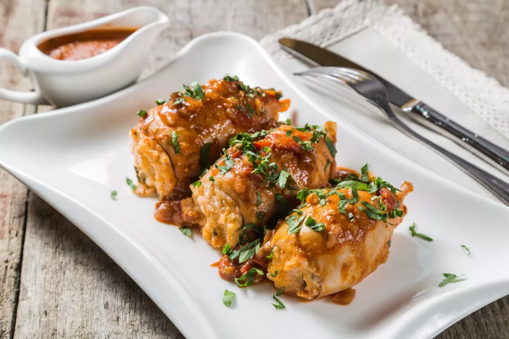 Squid stuffed with rice, olives and feta cheese in tomato sauce on a table of old boards / Foto: Starets