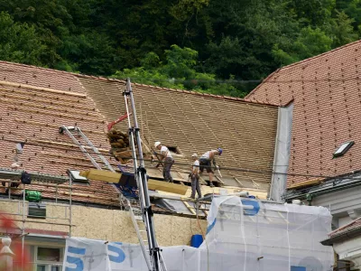 Roofers doing renovation work on rooftop at the old town of City of Ljubljana on a cloudy summer day. Photo taken August 9th, 2023, Ljubljana, Slovenia. / Foto: Michael Derrer Fuchs