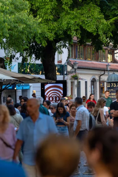 Capturing the lively atmosphere of a European summer, this shot shows a bustling pedestrian street in Ljubljana's historic center. Crowds of tourists and locals stroll past outdoor cafes and shops shaded by large trees. The warm natural light and vibrant urban energy make it ideal for travel guides, city lifestyle features, and tourism marketing showcasing popular destinations in Slovenia. / Foto: Aleksei Gorovoi Getty Images