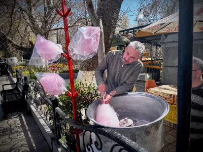 A man spins cotton candy for passersby in a public park near Road 2 in Tabriz, Iran, Thursday, April 9, 2026. (AP Photo/Francisco Seco)