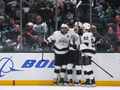 Los Angeles Kings right wing Adrian Kempe, center, celebrates his goal with center Anze Kopitar, left, and defenseman Brandt Clarke, right, against the Seattle Kraken during the third period of an NHL hockey game Monday, April 13, 2026, in Seattle. (AP Photo/Lindsey Wasson)