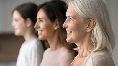 Happy attractive old 65s woman standing in row with young adult 30s daughter and little 7s granddaughter, smiling, look straight, side profile faces view. Three generations family portraits, close up