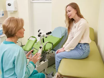 Professional female doctor looking at her patient and discussing female disorders