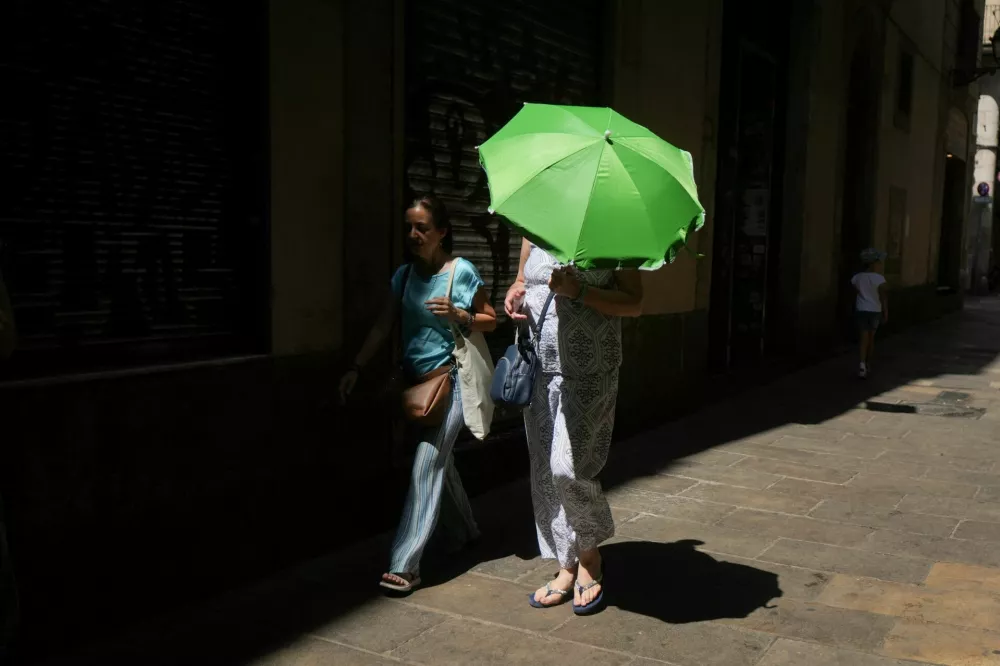 A woman carries an umbrella for shade from the heat as she walks around El Born, in Barcelona, Spain, August 9, 2025. REUTERS/Bruna Casas