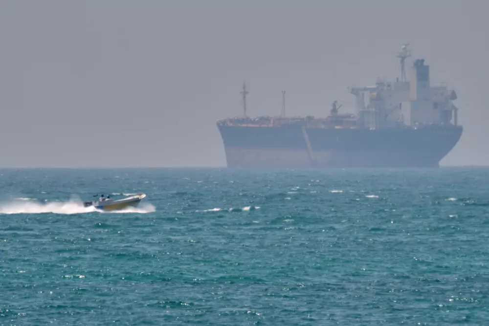 A boat sails past a tanker anchored on the Strait of Hormuz off the coast Qeshm island, Iran, Saturday, April 18, 2026. (AP Photo/Asghar Besharati)
