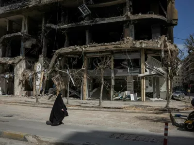 A woman walks past damaged buildings amid a 10-day ceasefire between Lebanon and Israel, in the southern suburbs of Beirut, Lebanon, April 20, 2026. REUTERS/Marko Djurica   TPX IMAGES OF THE DAY