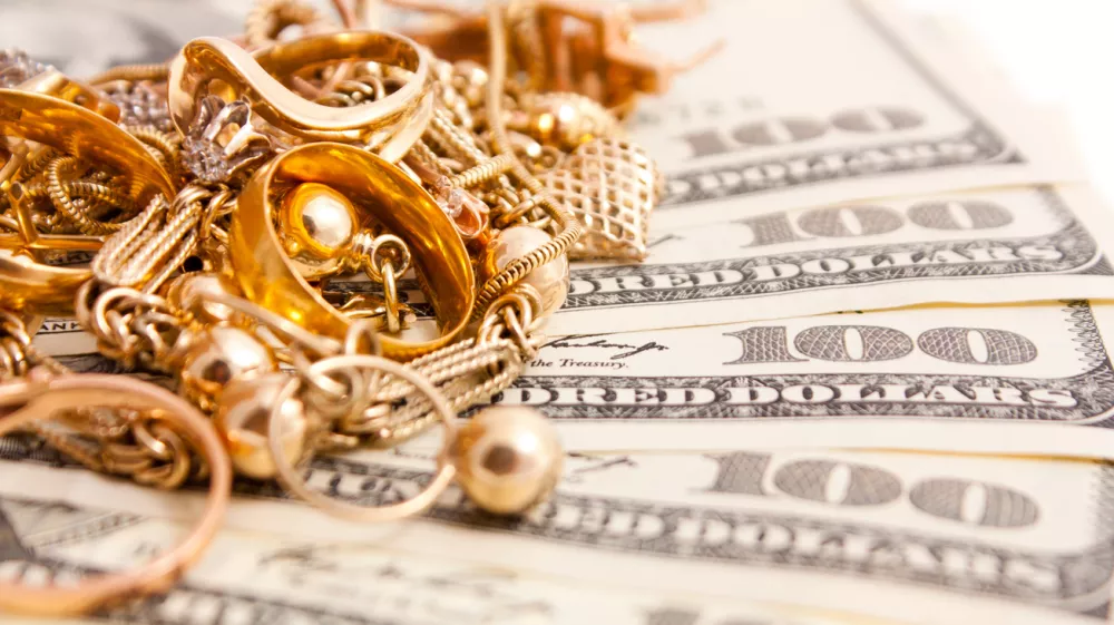 Closeup photo of jewelry on dollars. Isolated on white background. / Foto: Gerakl Getty Images/istockphoto