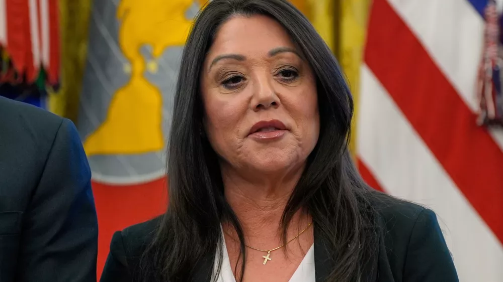 FILE - Labor Secretary Lori Chavez-DeRemer listens as President Donald Trump speaks with reporters while signing executive orders in the Oval Office of the White House, April 23, 2025, in Washington. (AP Photo/Alex Brandon, File)