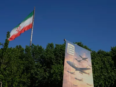 A banner shows a graphic depicting Iranian-built drones with a sign in Farsi that reads: "Arash drone is the nightmare for Iran's enemies," as an Iranian flag waves at left, in Tehran, Iran, Tuesday, April 21, 2026. (AP Photo/Vahid Salemi)