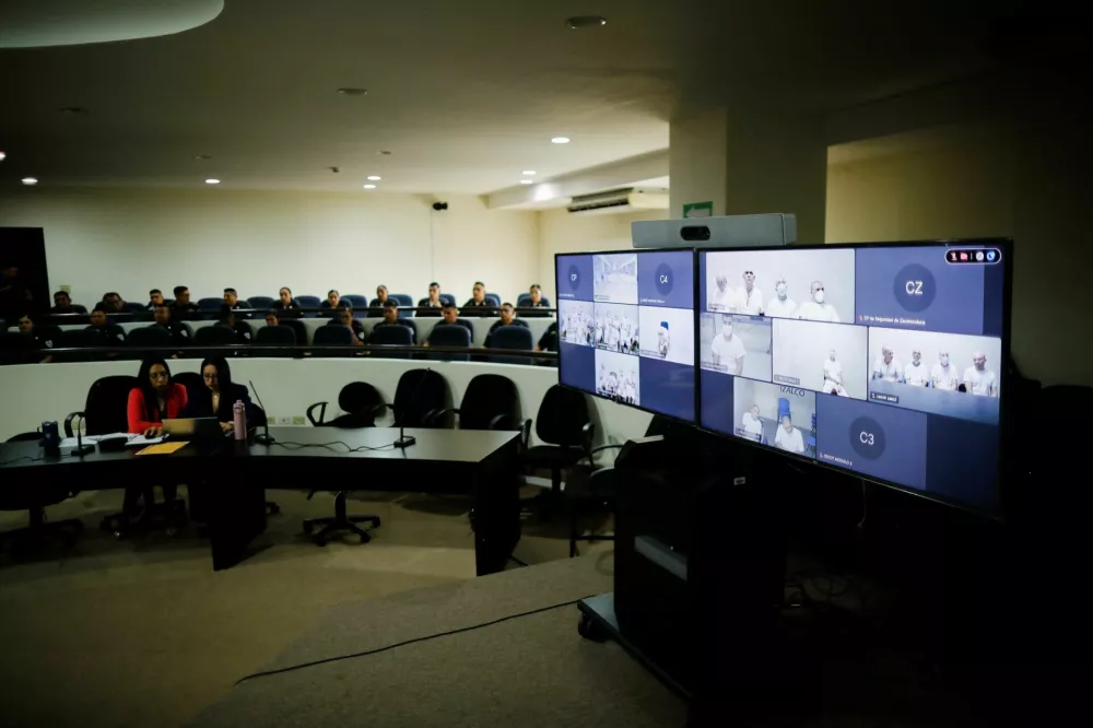 Members of Mara Salvatrucha, also known as MS-13 gang, are seen on a monitor as they attend an open hearing by El Salvador prosecutors against 486 members of the gang, who are accused of more than 47,000 crimes committed between 2012 and 2022, according to a statement from the Attorney General's Office, at the Judicial Center Against Organized Crime in Soyapango, El Salvador April 21, 2026. REUTERS/Jose Cabezas