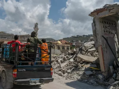 Children stand on a pick-up as they ride past buildings damaged by an Israeli strike in Mansouri village, southern Lebanon, amid a 10-day ceasefire between Lebanon and Israel, April 21, 2026. REUTERS/Zohra Bensemra