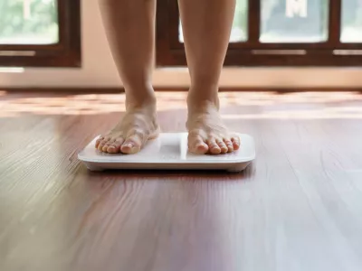 Fat diet and scale feet standing on electronic scales for weight control. Measurement instrument in kilogram for a diet control.