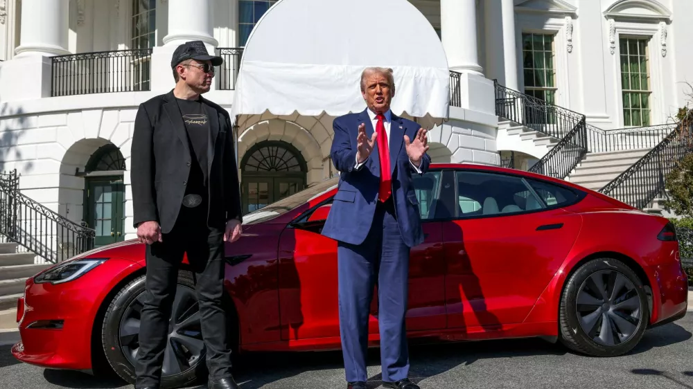 FILE PHOTO: U.S. President Donald Trump talks to the media next to Tesla CEO Elon Musk, with a Tesla car in the background, at the White House in Washington, D.C., U.S., March 11, 2025. REUTERS/Kevin Lamarque/File Photo