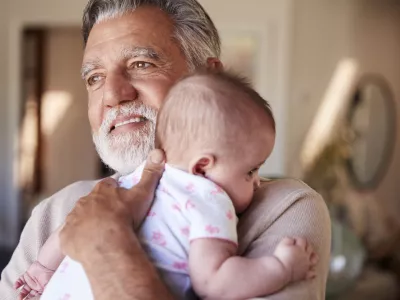 Hispanic grandfather holding his baby grandson, head and shoulders, close up